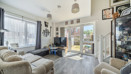 Bright living room with sofas, large windows, TV and doors opening to the garden.