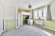 Bedroom with bunk bed, desk, window and carpeted floor.