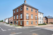Red brick apartment building on a street corner with nearby residential homes.