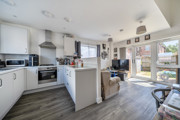 Open-plan kitchen with white cabinets, breakfast bar and adjoining living area.