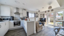 Open-plan kitchen with white cabinets, breakfast bar and adjoining living area.