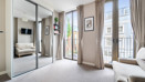 Bedroom with mirrored wardrobe doors and windows opening onto a balcony.
