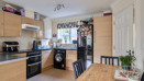 Kitchen with wooden-effect cabinets, appliances and small dining table with chairs.