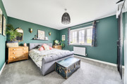 Bedroom with double bed, chest of drawers, window and green walls.