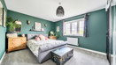Bedroom with double bed, chest of drawers, window and green walls.