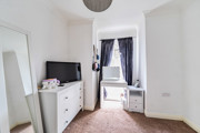 Bedroom with chest of drawers, vanity table, mirror, desk and window.
