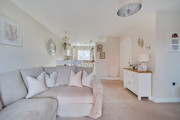 Open-plan living area with sofa, sideboard and decorative wall mirrors.