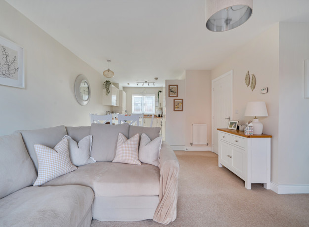 Open-plan living area with sofa, sideboard and decorative wall mirrors.