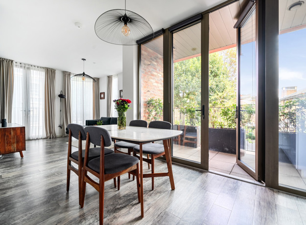 Dining area with dining table beside floor-to-ceiling balcony doors.