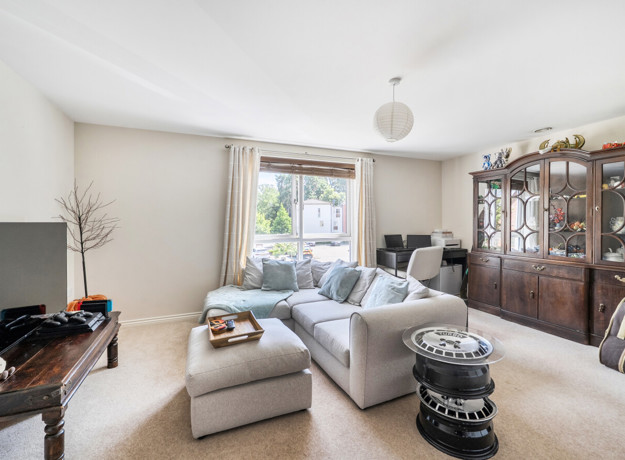 Living room with sofa, cabinet, TV and window with curtains.