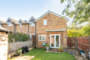 Back garden with lawn, wooden shed and fenced boundaries.