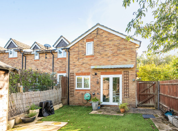 Back garden with lawn, wooden shed and fenced boundaries.