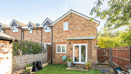 Back garden with lawn, wooden shed and fenced boundaries.