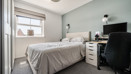 Bedroom with double bed, desk, chair, and wardrobe beside a window.