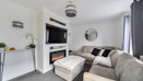 Living room with corner sofa, footstool, fireplace, television and shelving.